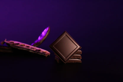 Eine angebrochene Tafel der Premium Johannisbrot Schokolade, bei der das Innere mit den Johannisbrotstückchen sichtbar wird.
