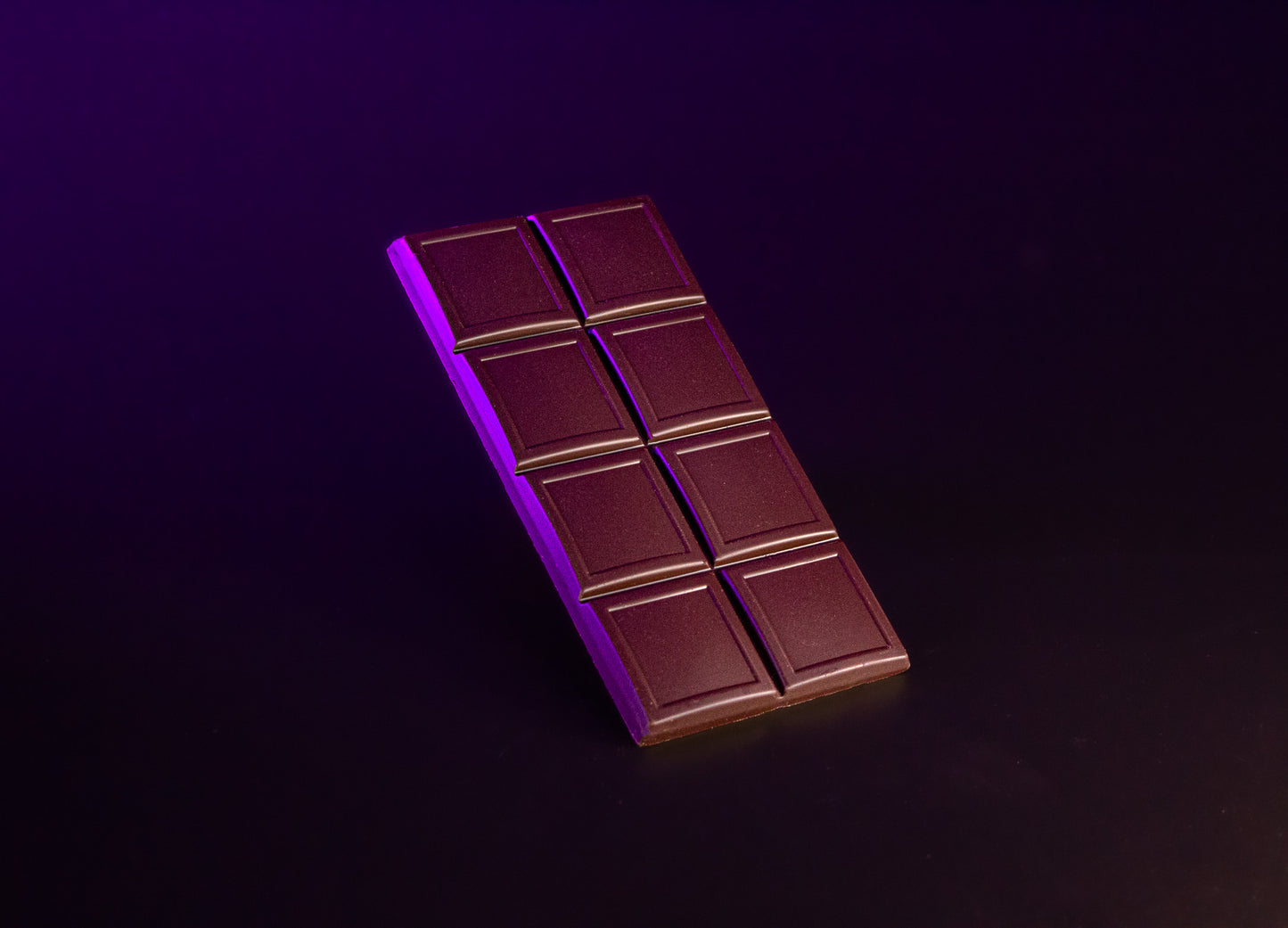 Nahaufnahme eines Stücks der Premium Johannisbrot Schokolade, die Beschaffenheit der Schokolade und die Johannisbrotstückchen sind gut zu erkennen.